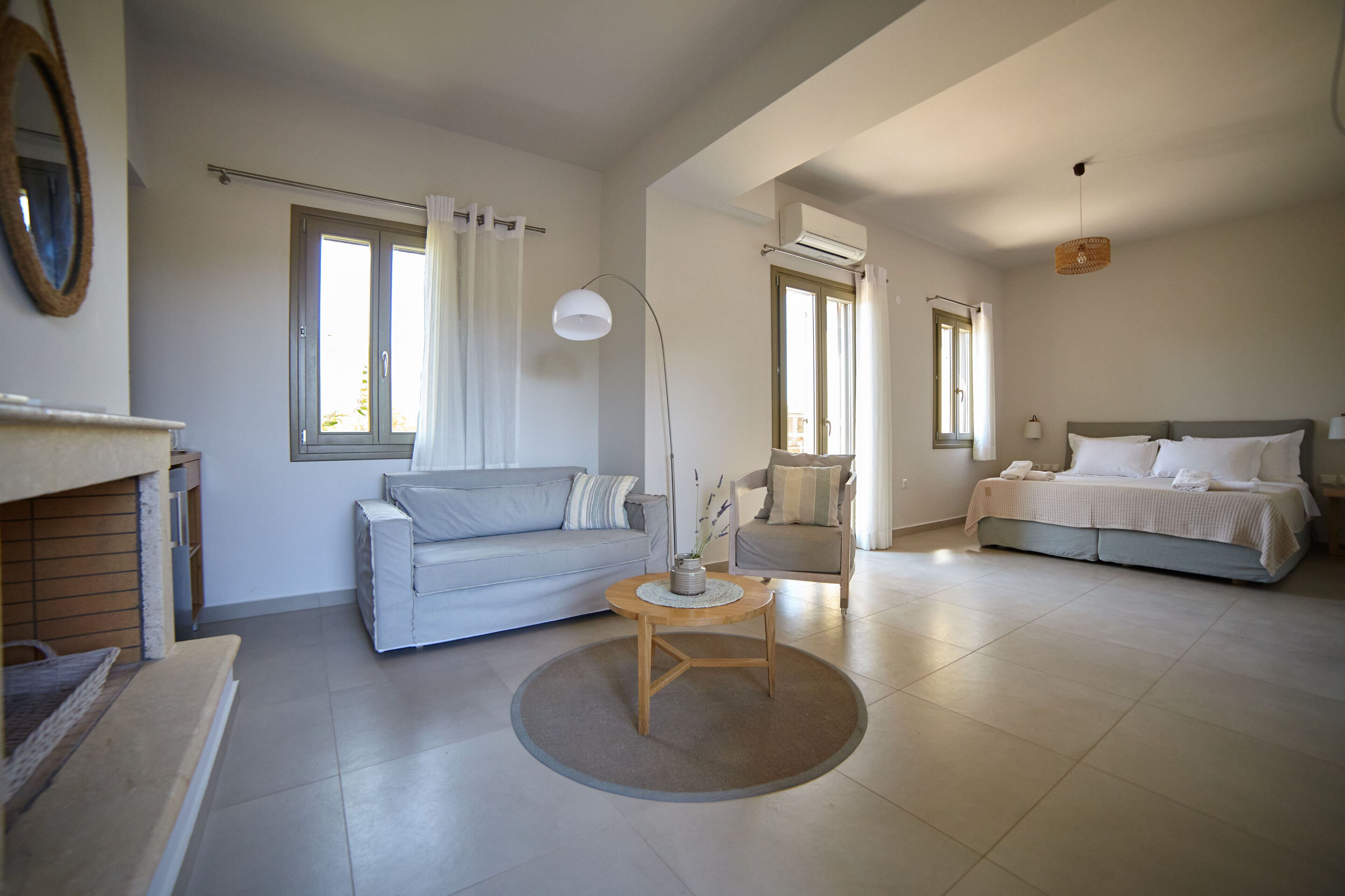 A modern, well-lit living room with a sofa, a round coffee table, and a bed with a headboard.