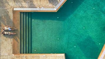 Alberca al aire libre, sombrillas en la alberca y camastros