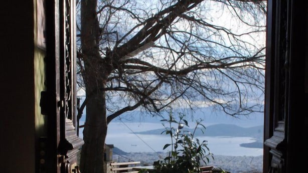 A stone pathway leading to a garden with a bench and a view of a lake and mountains. - Archontiko Stafylopati (Volos)