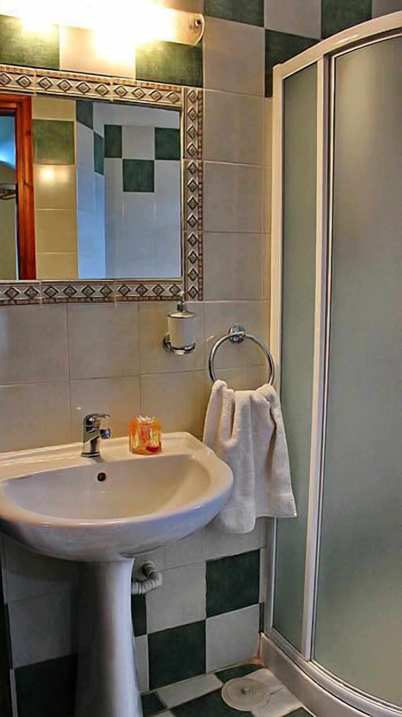 A bathroom with a sink, mirror, towel rack, and shower.