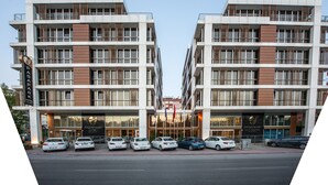 Un hotel moderno con fachada simétrica, varios balcones y una entrada despejada.