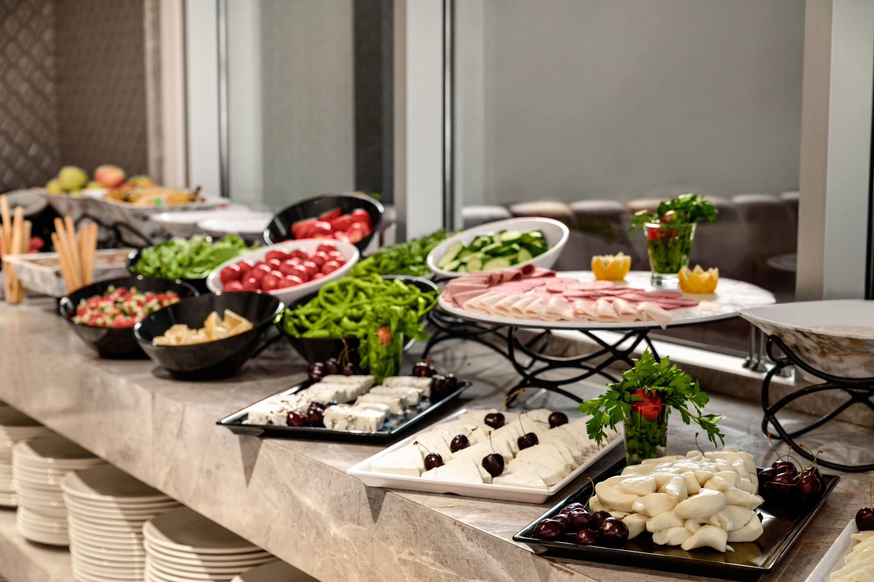 Una mesa de buffet con diversos alimentos y un vaso de agua.