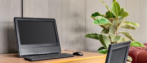 Una laptop sobre un escritorio de madera con una planta a su lado.