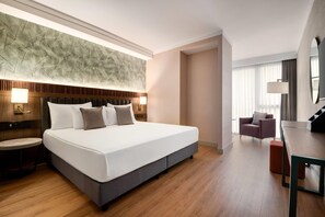 Een hotelkamer met een groot bed, nachtkastjes, een bureau en een stoel.