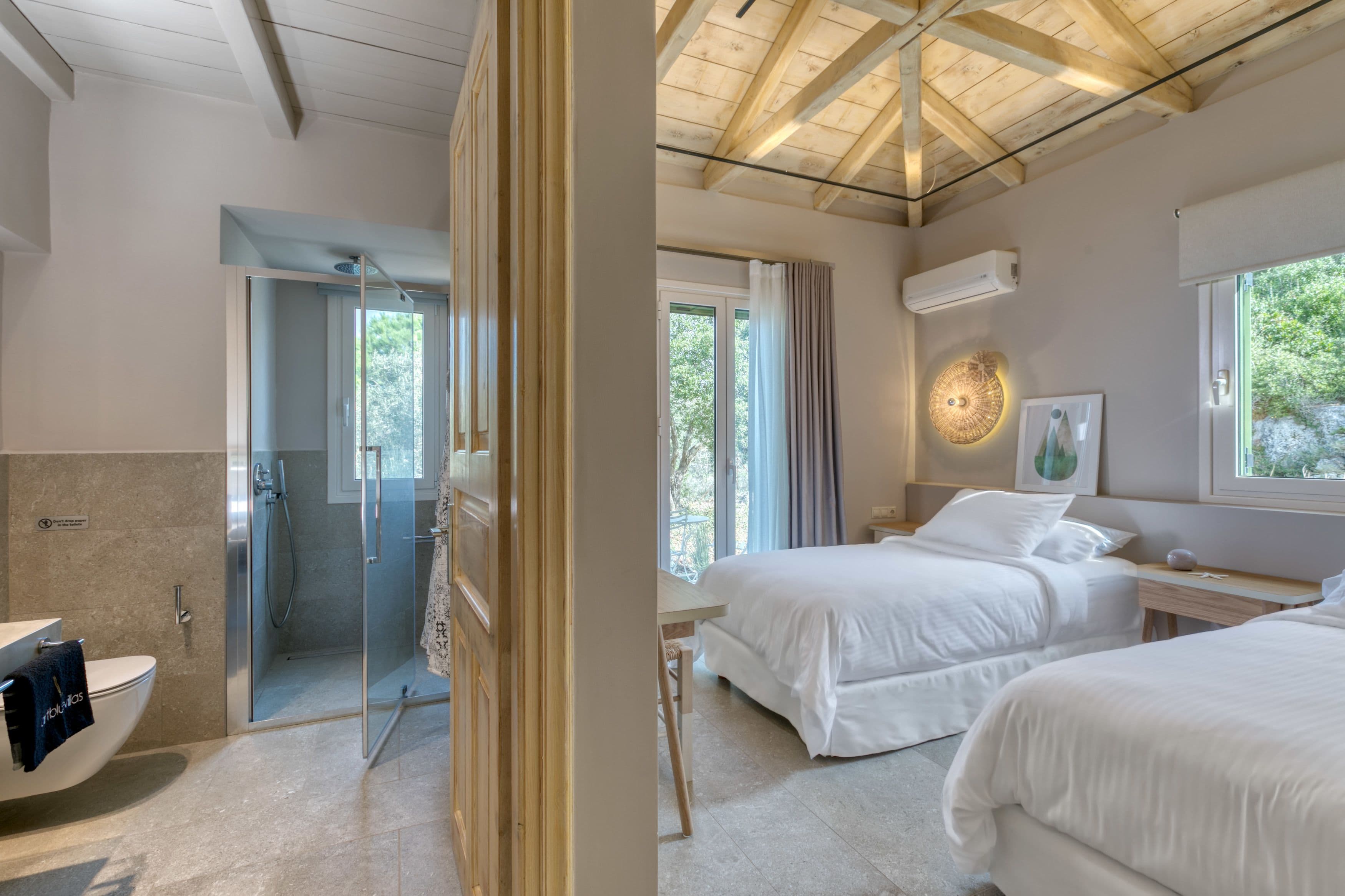 Una habitación de hotel con ducha, cama, mesita de noche y ventana.