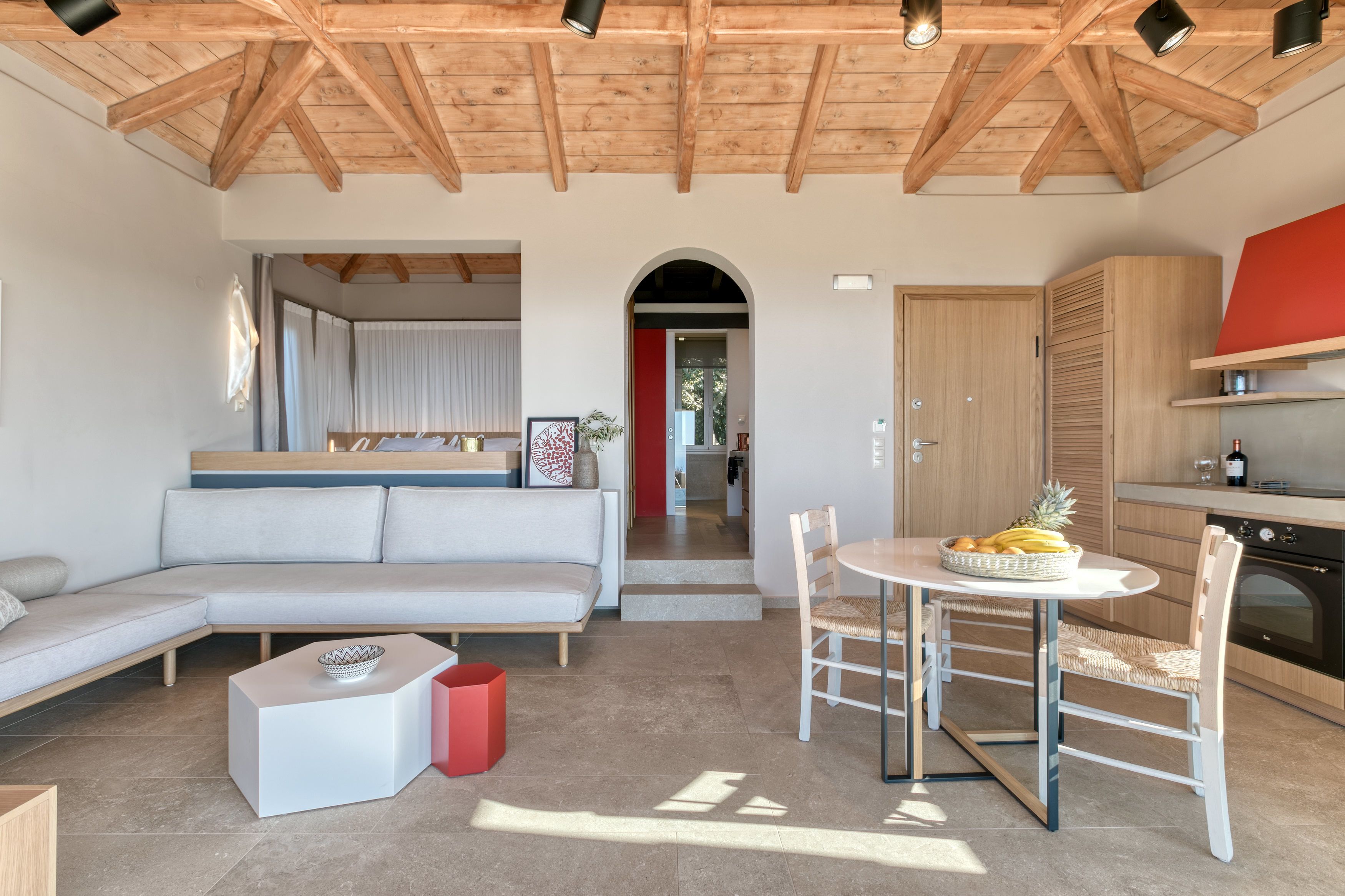 Un salon moderne comprenant un canapé, une table à manger avec des chaises, un coin cuisine et un plafond en bois.