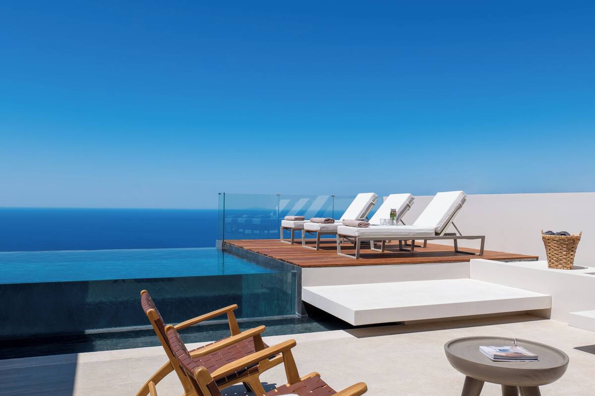 A rooftop infinity pool with lounge chairs and a small table.