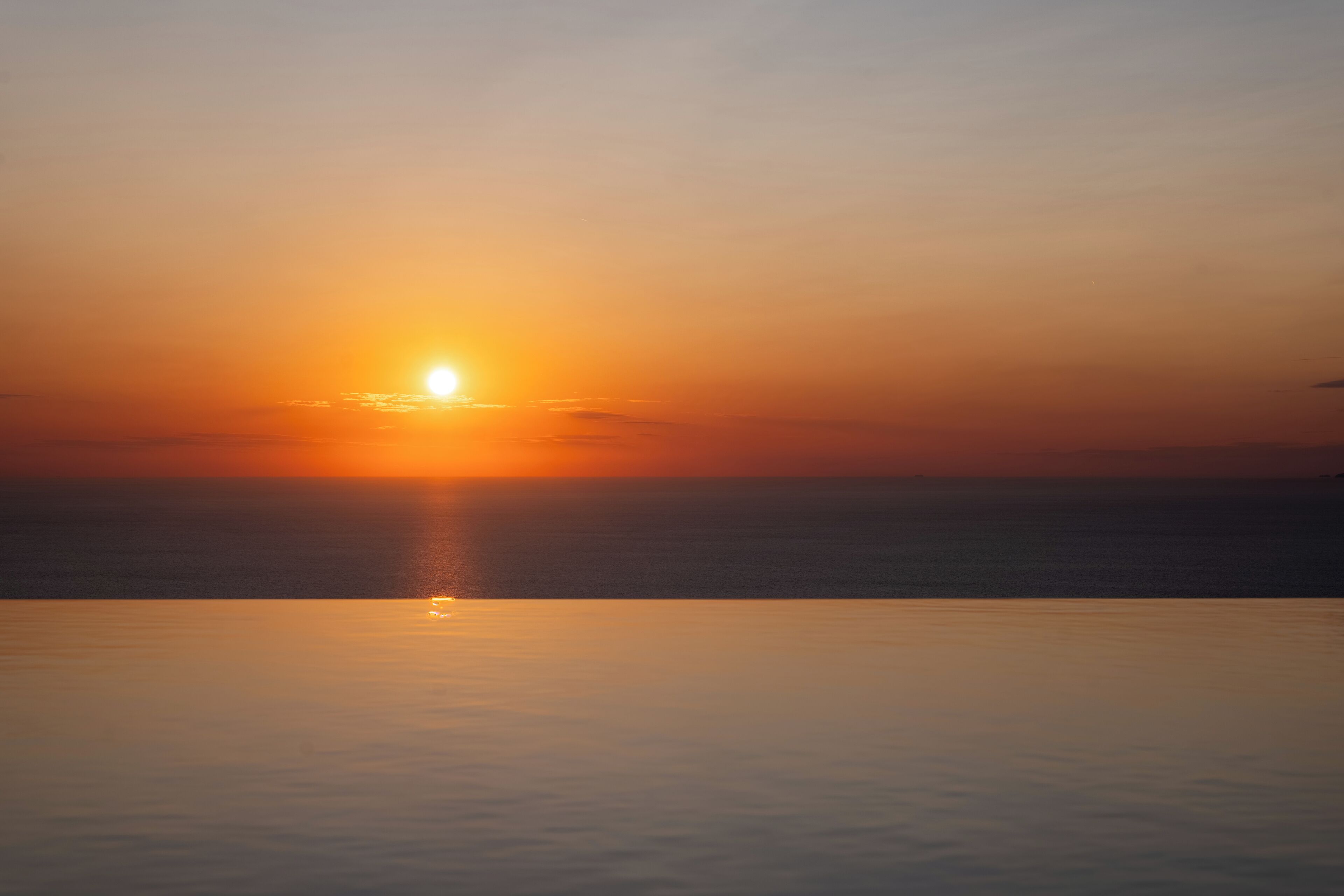 Un atardecer sobre un mar tranquilo con horizonte despejado.