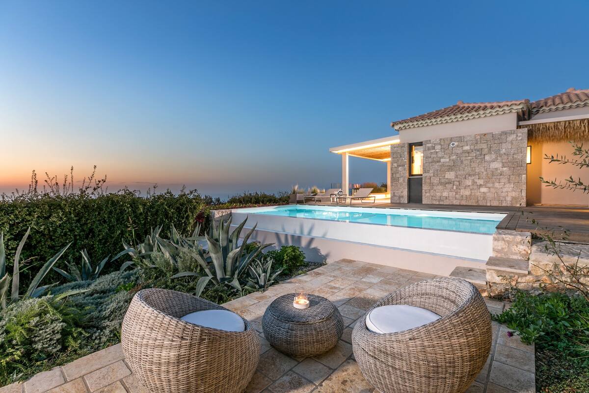 A modern outdoor pool area with stone walls and wicker furniture.