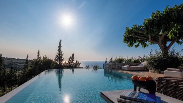 An infinity pool with clear water, surrounded by greenery and a view of the sea. - Art Blue Villas (Lefkada)