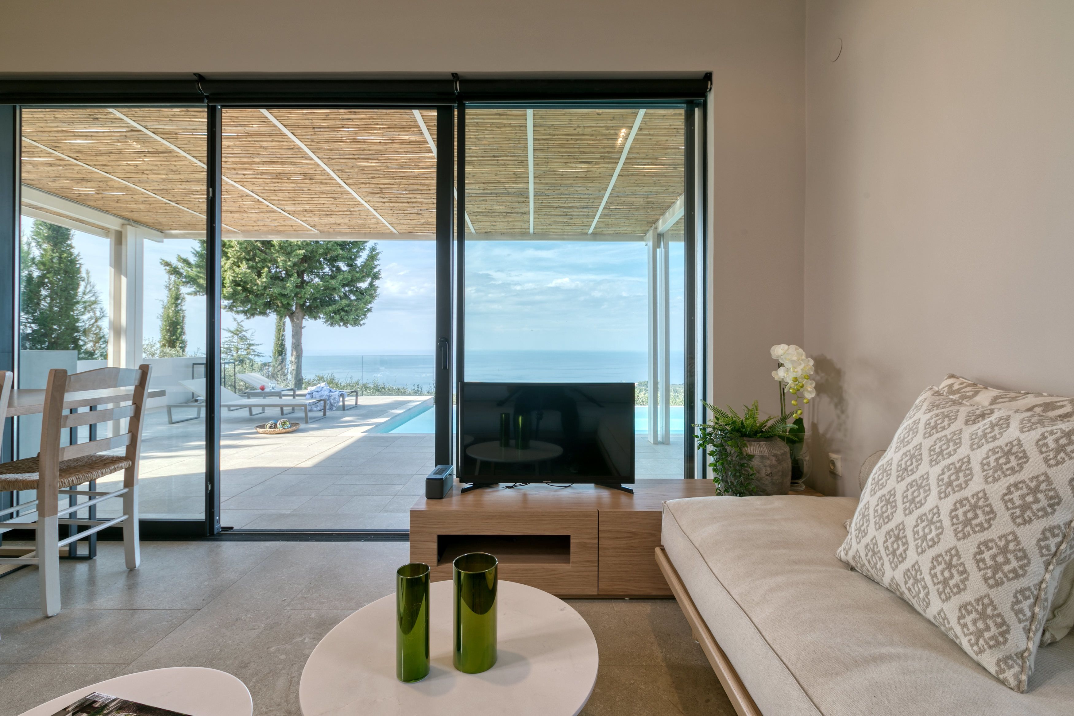 Una sala de estar moderna con un televisor grande, un sofá y un comedor con mesa y sillas.