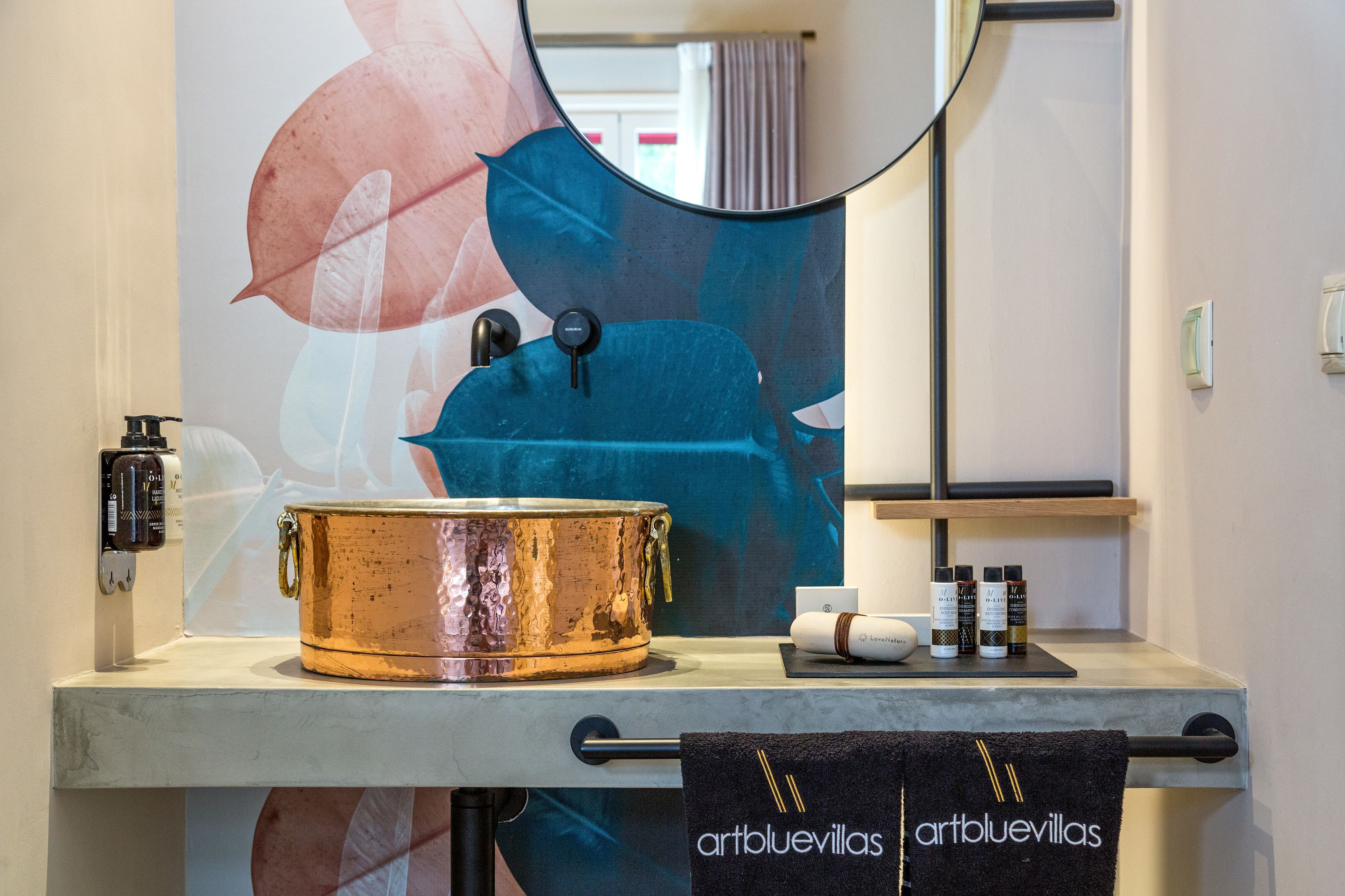 A bathroom with a copper-colored bathtub, a mirror, and a towel rack with towels.