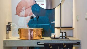 A bathroom with a copper-colored bathtub, a mirror, and a towel rack with towels.
