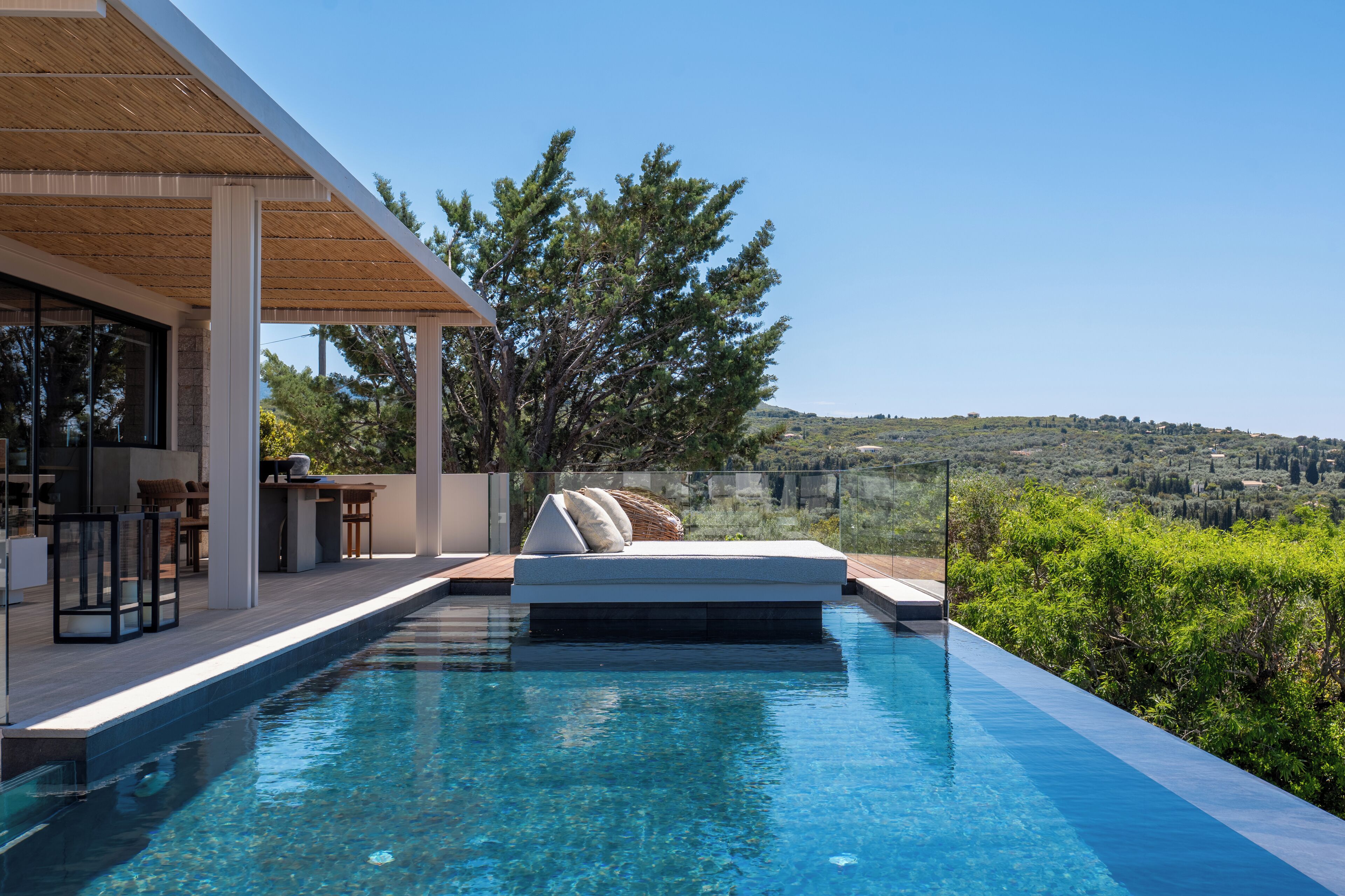 A modern outdoor pool area with a built-in seating area and a view of the surrounding landscape.