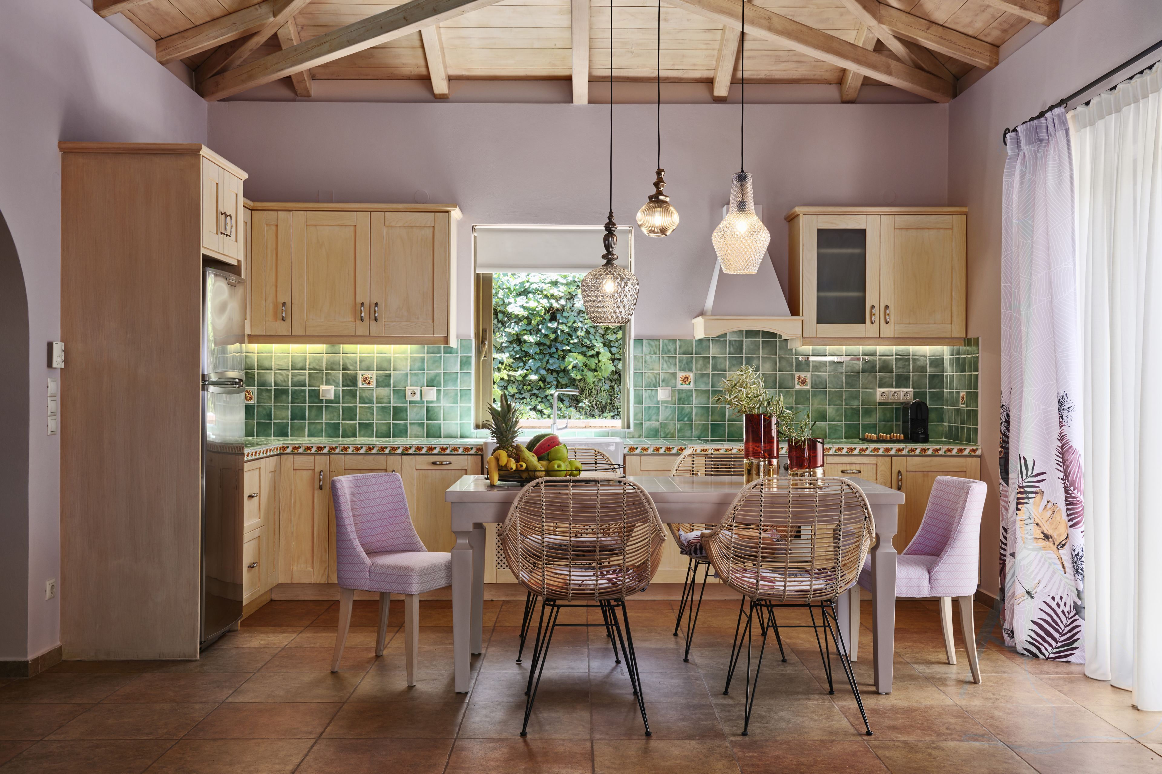 A kitchen with wooden cabinets, a dining table with chairs, and a view of greenery outside.