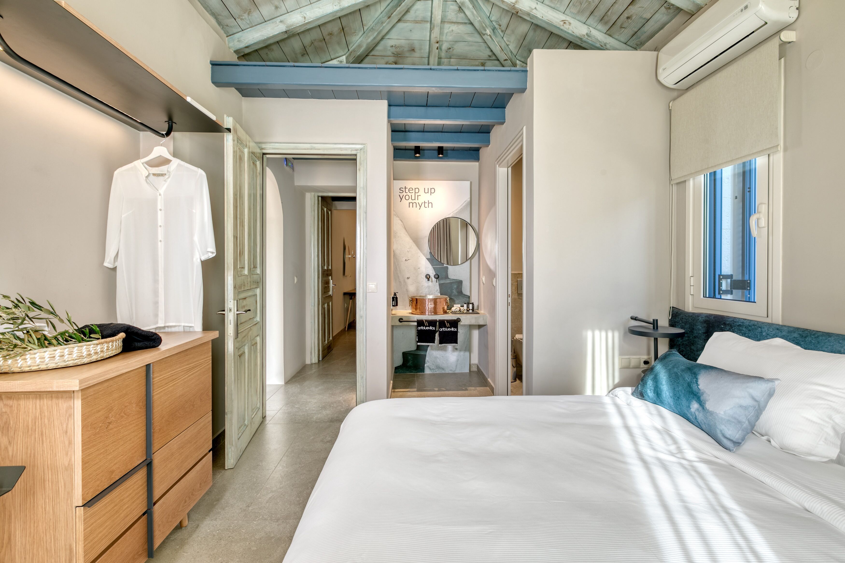 Een slaapkamer met een bed, een dressoir, een spiegel en een raam.