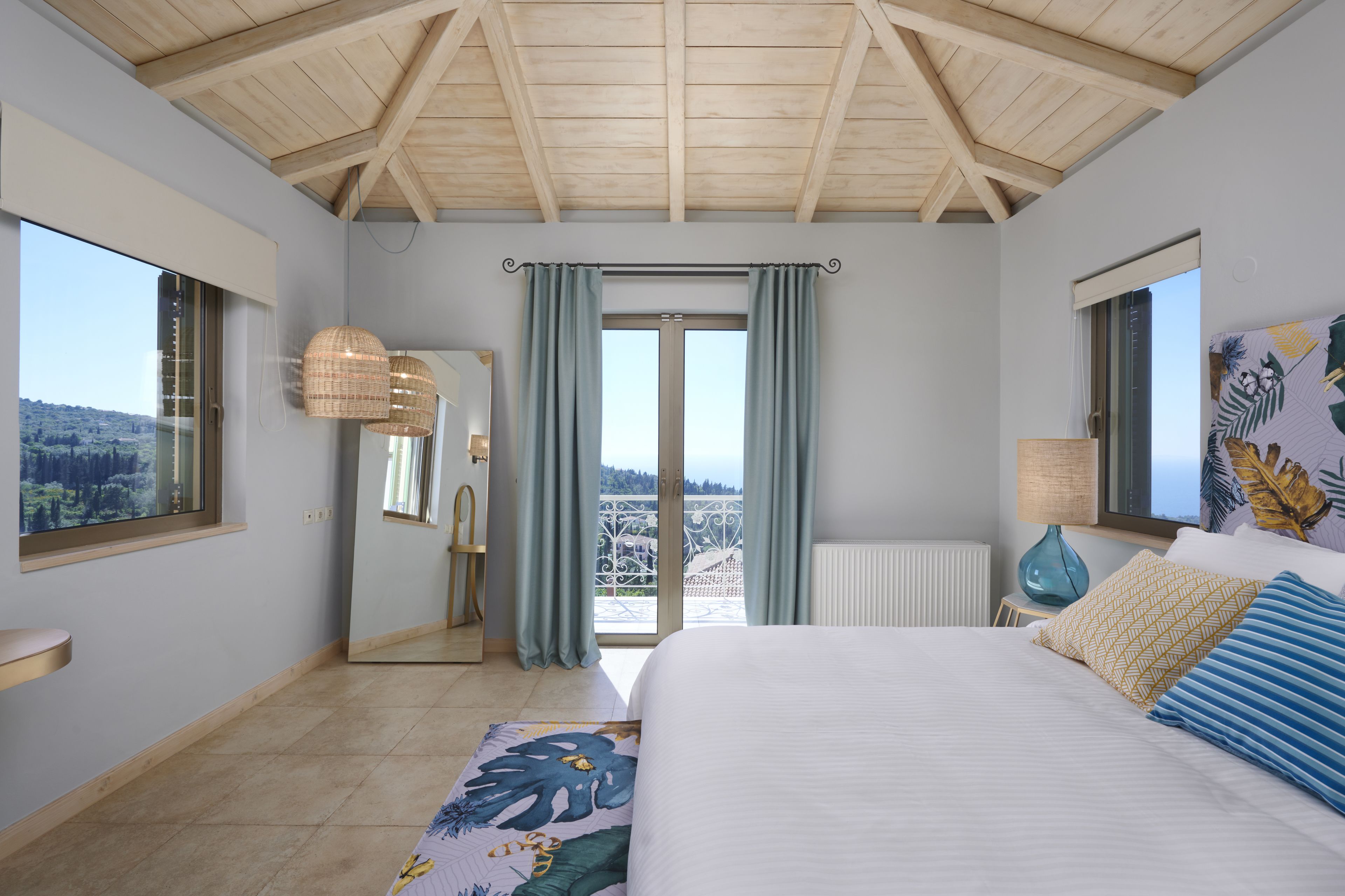 Une chambre avec un grand lit, une fenêtre, un miroir et une vue sur l’extérieur.