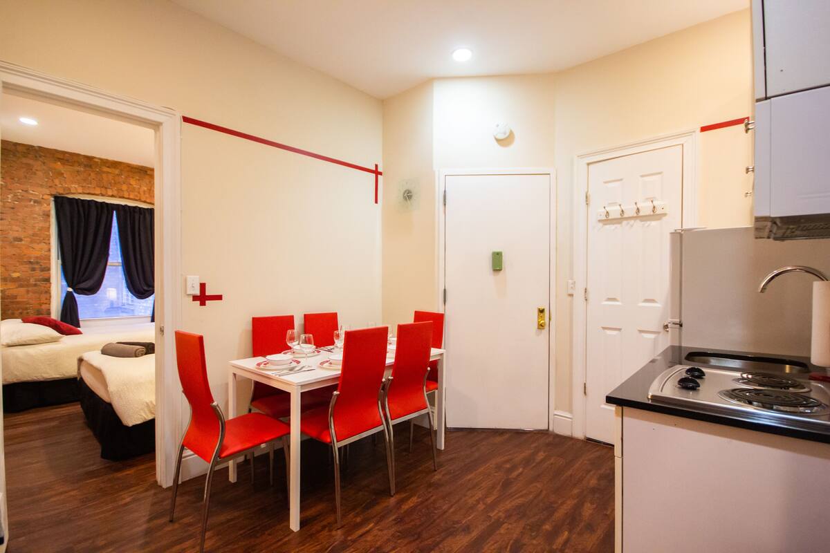 A compact hotel room with a dining area, a kitchenette, and a separate bedroom.