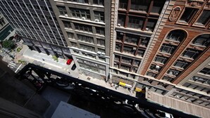 Un edificio de gran altura con varios pisos, ventanas amplias y una combinación de estilos arquitectónicos.