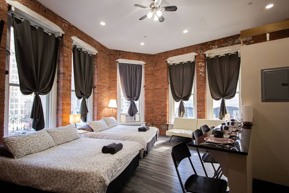 A hotel room with two beds, a dining area, and a view of the city.