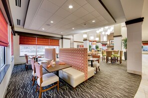 A modern hotel lobby with seating areas, a patterned carpet, and large windows.