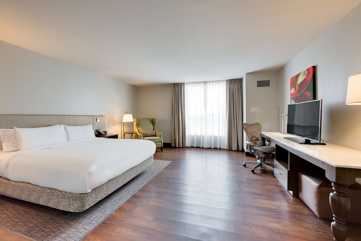 A hotel room with a large bed, a desk with a computer, a chair, and a TV.