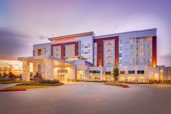 A modern hotel with a prominent entrance, multiple floors, and a well-lit facade.