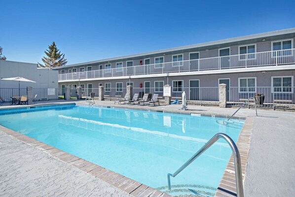 Un hôtel doté d’une piscine, d’un espace extérieur aménagé et d’un bâtiment à deux étages avec des balcons.