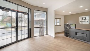 A hotel reception area with a modern design, featuring a reception desk, a large glass door entrance, and a view of the outside. - Quality Inn Idaho Falls (Idaho Falls)