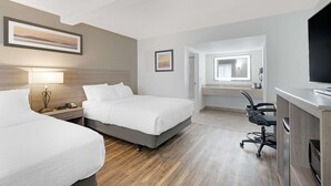 A hotel room with two beds, a desk, a chair, a TV, and a bathroom visible through an open door. - Quality Inn Idaho Falls (Idaho Falls)