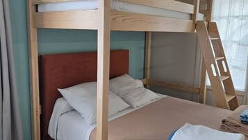 A bunk bed with a wooden ladder, a red headboard, and a beige bedspread.