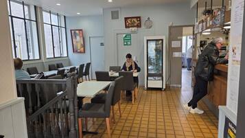 A restaurant with indoor seating, a refrigerator, and a counter.