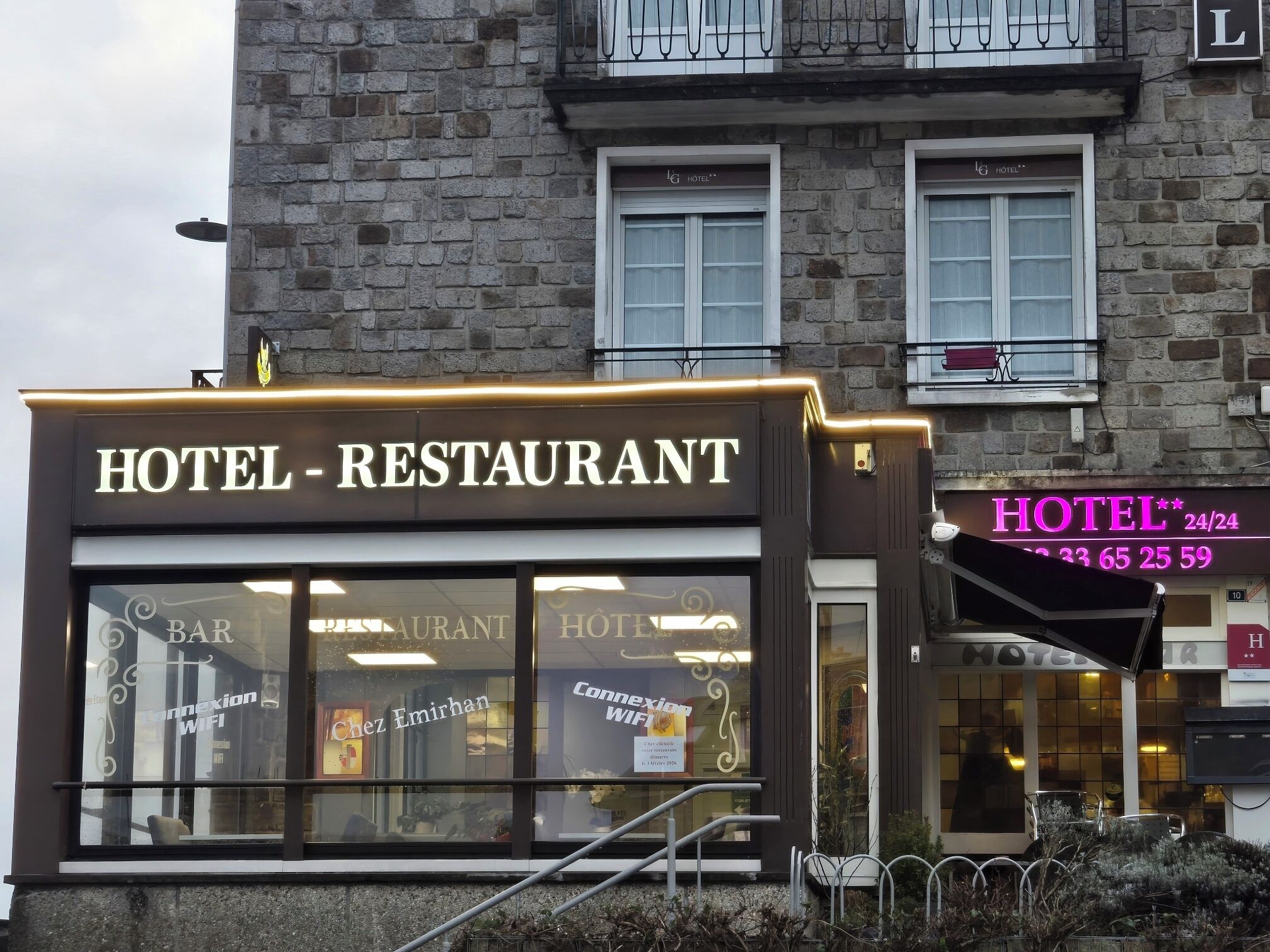 A hotel with a restaurant and bar, featuring a stone facade and large windows.
