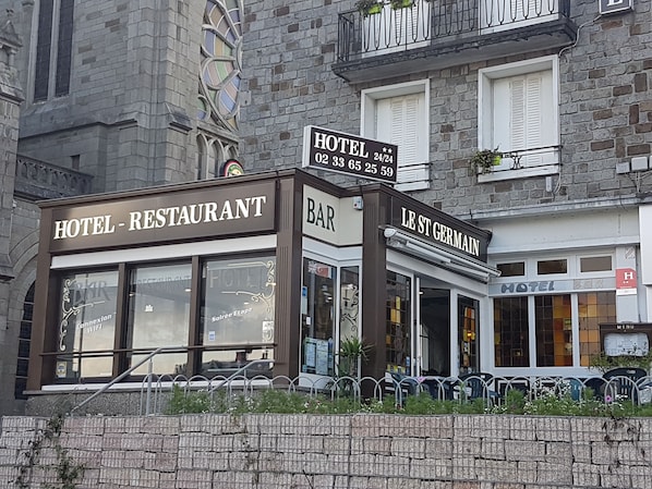 Un hotel con restaurante y bar, que presenta un estilo arquitectónico europeo clásico con fachada de piedra y ventanas grandes.