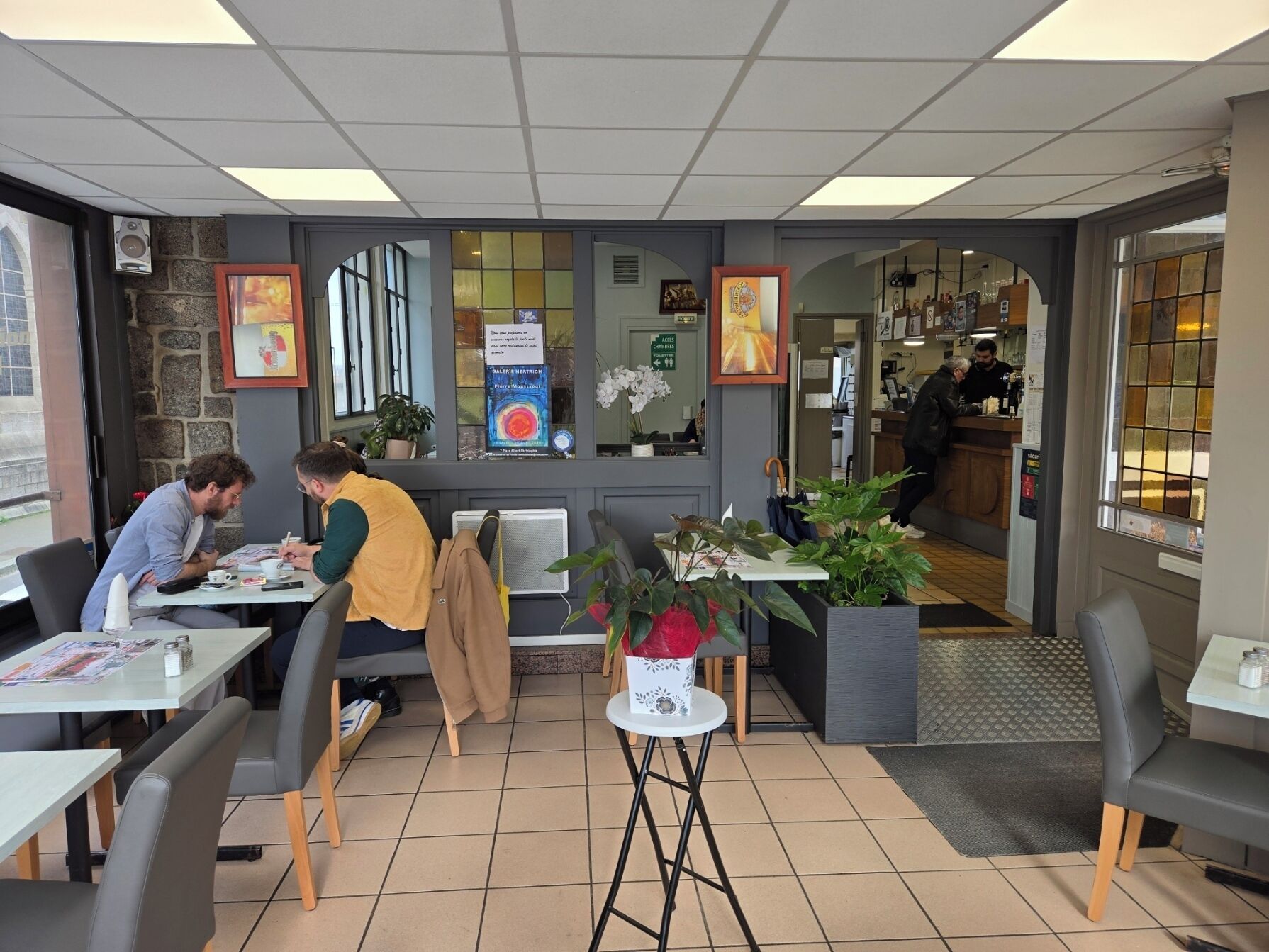 A cafe with tables, chairs, a counter, and a display of books.