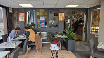 A cafe with tables, chairs, a counter, and a display of books.