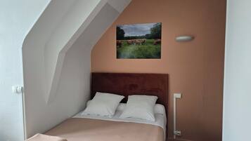 Une chambre à coucher avec un lit, une tête de lit, un tableau accroché au mur et une fenêtre.