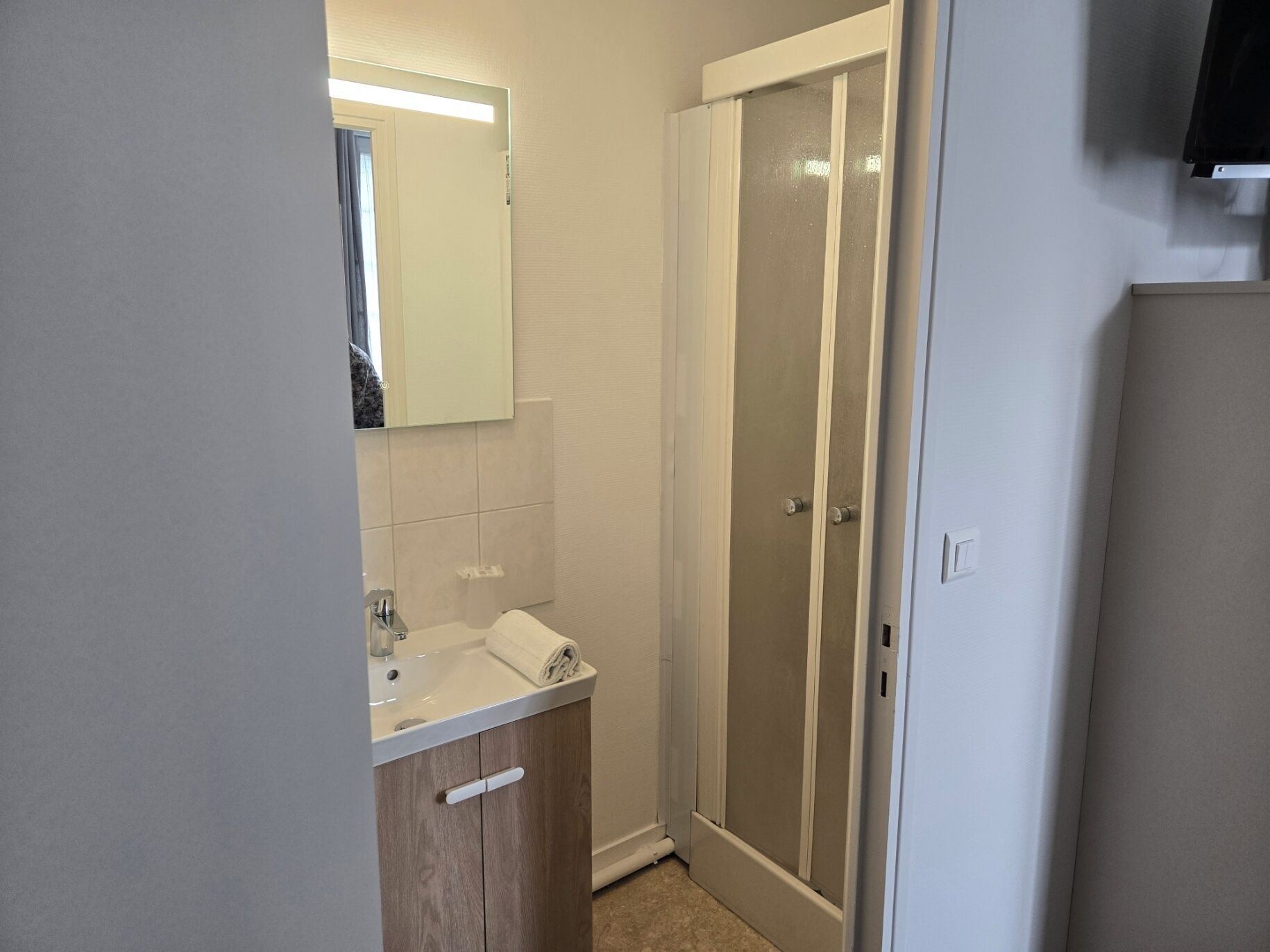 A bathroom with a shower, a sink, and a mirror.