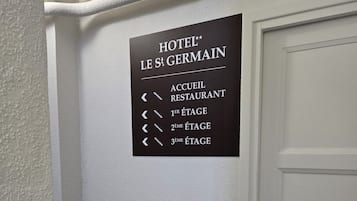 A wall sign with directional arrows pointing to the hotel reception, first, second, and third floors, and a restaurant.