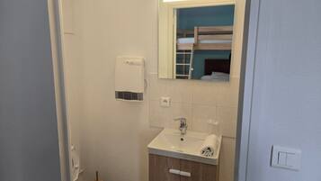 Un baño pequeño con inodoro, lavamanos, espejo y toallero.