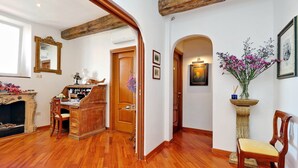 A spacious room with hardwood floors, a wooden desk, a chair, a fireplace, and a large mirror. - Terrazze Navona (Rome)