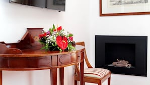 A dining area with a wooden table, a chair, a bouquet of flowers, a fireplace, and a framed picture on the wall. - Terrazze Navona (Rome)