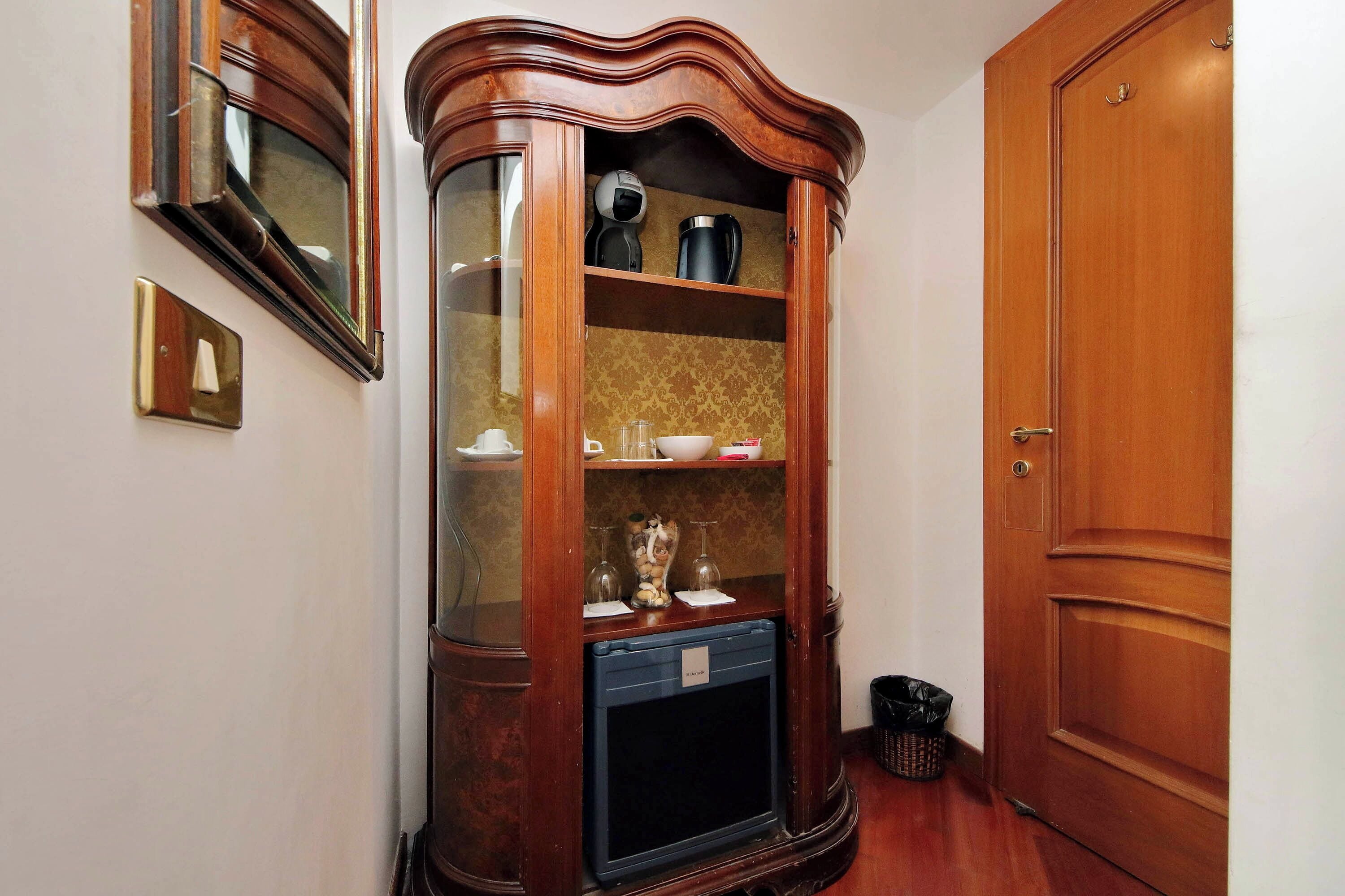 A wooden cabinet with glass doors containing kitchen appliances and a small refrigerator.