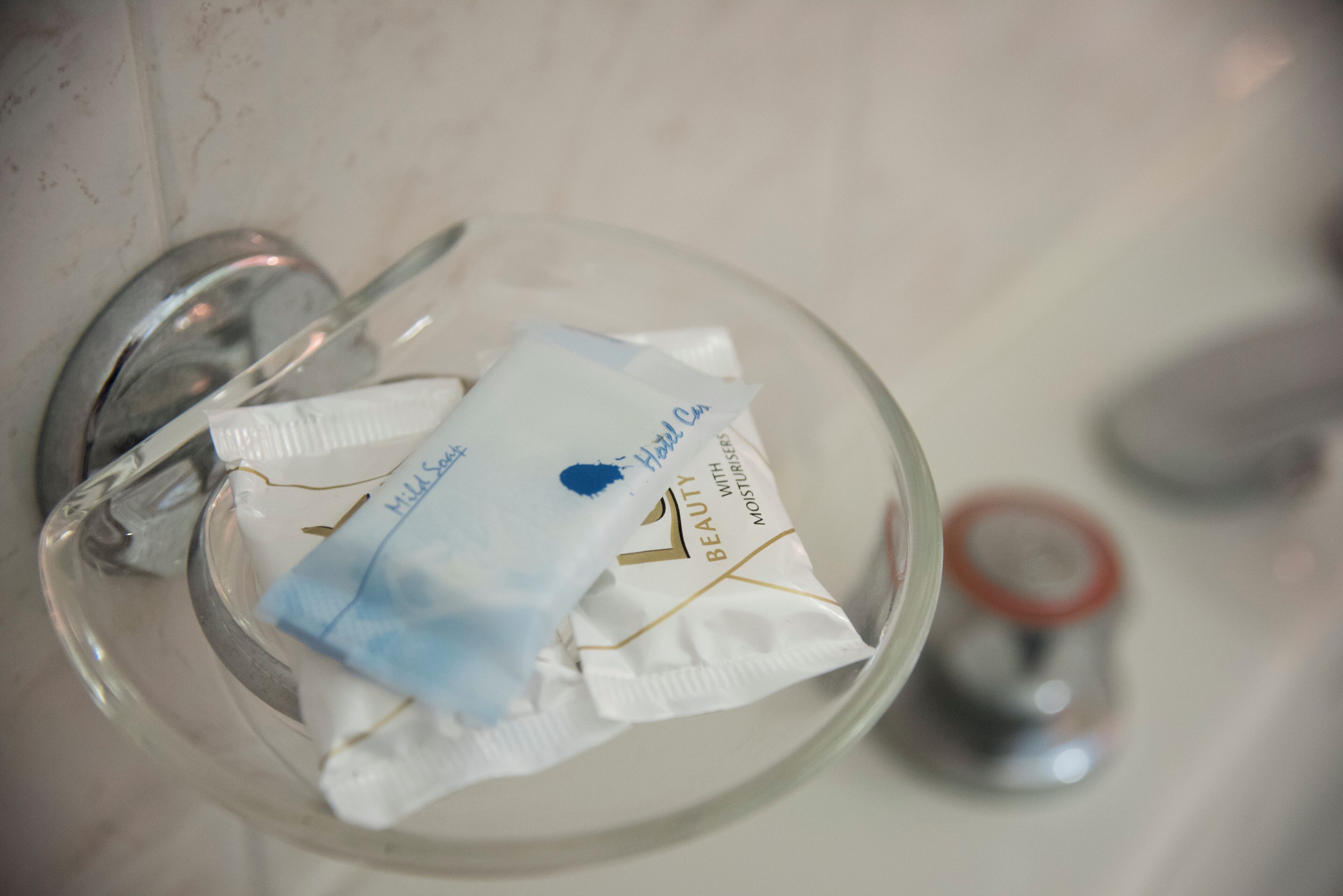 Un tazón de vidrio con un pañuelo de papel y un pequeño envase de crema.
