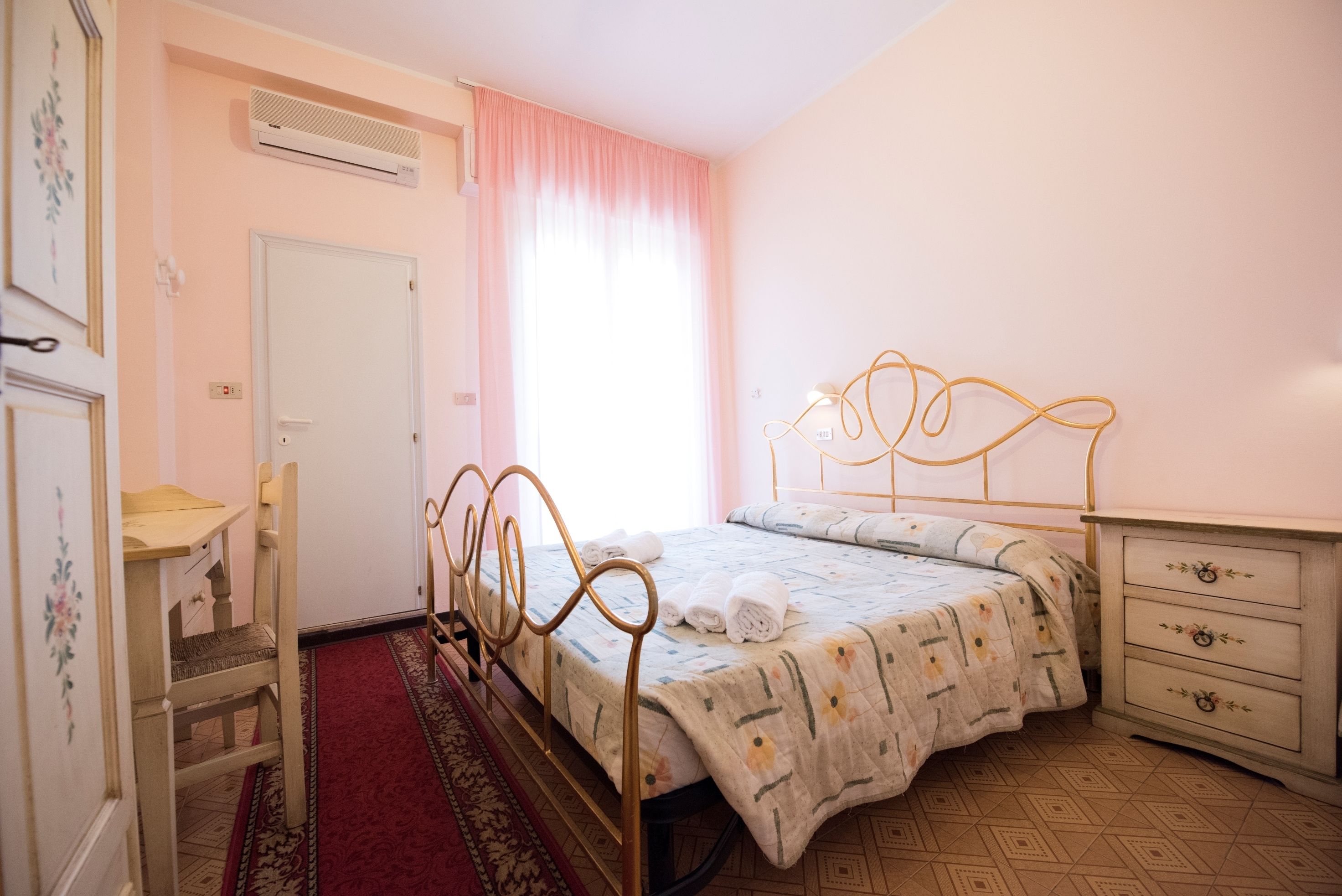 A bedroom with a bed, a dresser, a chair, and a door.