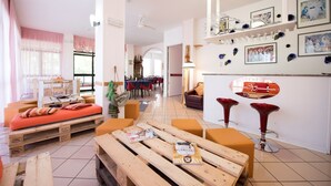 Una sala moderna con una mesa de centro de madera, asientos naranjas y una zona de comedor con sillas rojas.