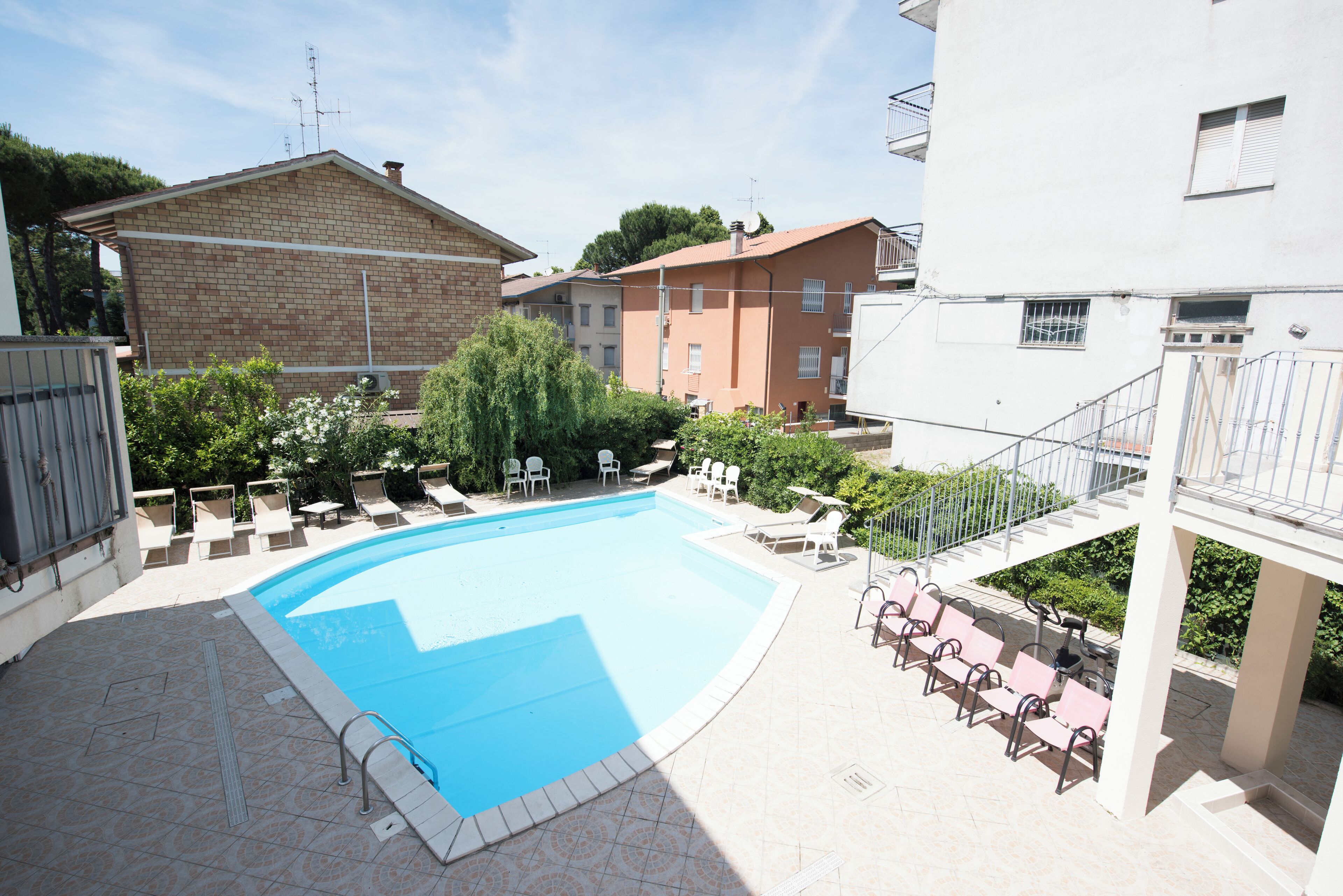 A swimming pool with lounge chairs and a staircase leading to an upper level.