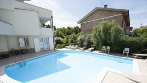 Una piscina con sillas de descanso y una pequeña zona de patio.