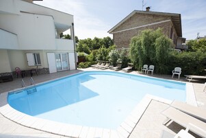 Una piscina al aire libre, sillones reclinables de piscina
