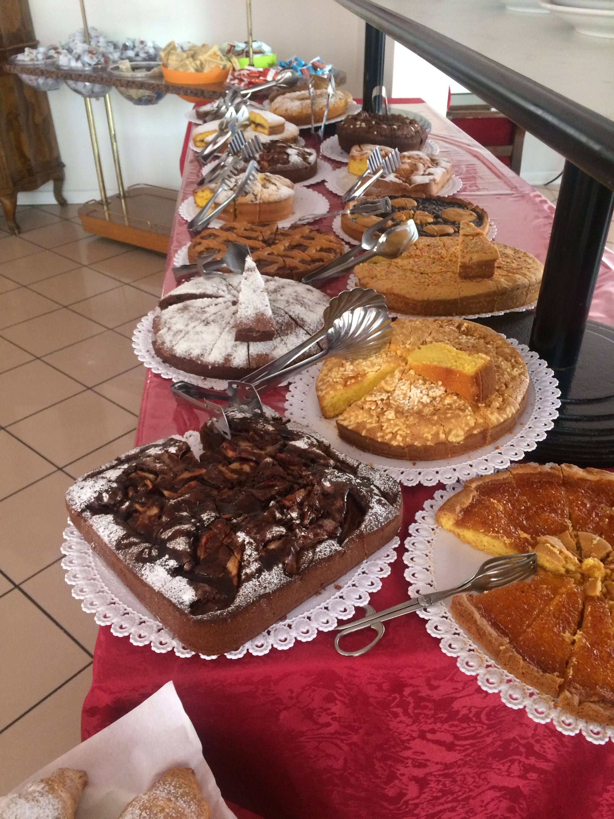 A buffet table with various desserts and a red tablecloth.
